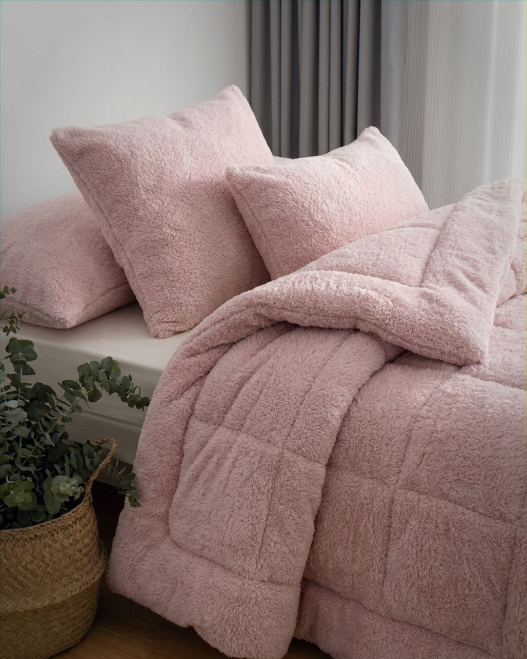 A cozy bed with deep purple bedding, large pillows, a knit throw, and a coffee cup sits in a neutral-toned room with pampas grass and a woven pendant light as decor.