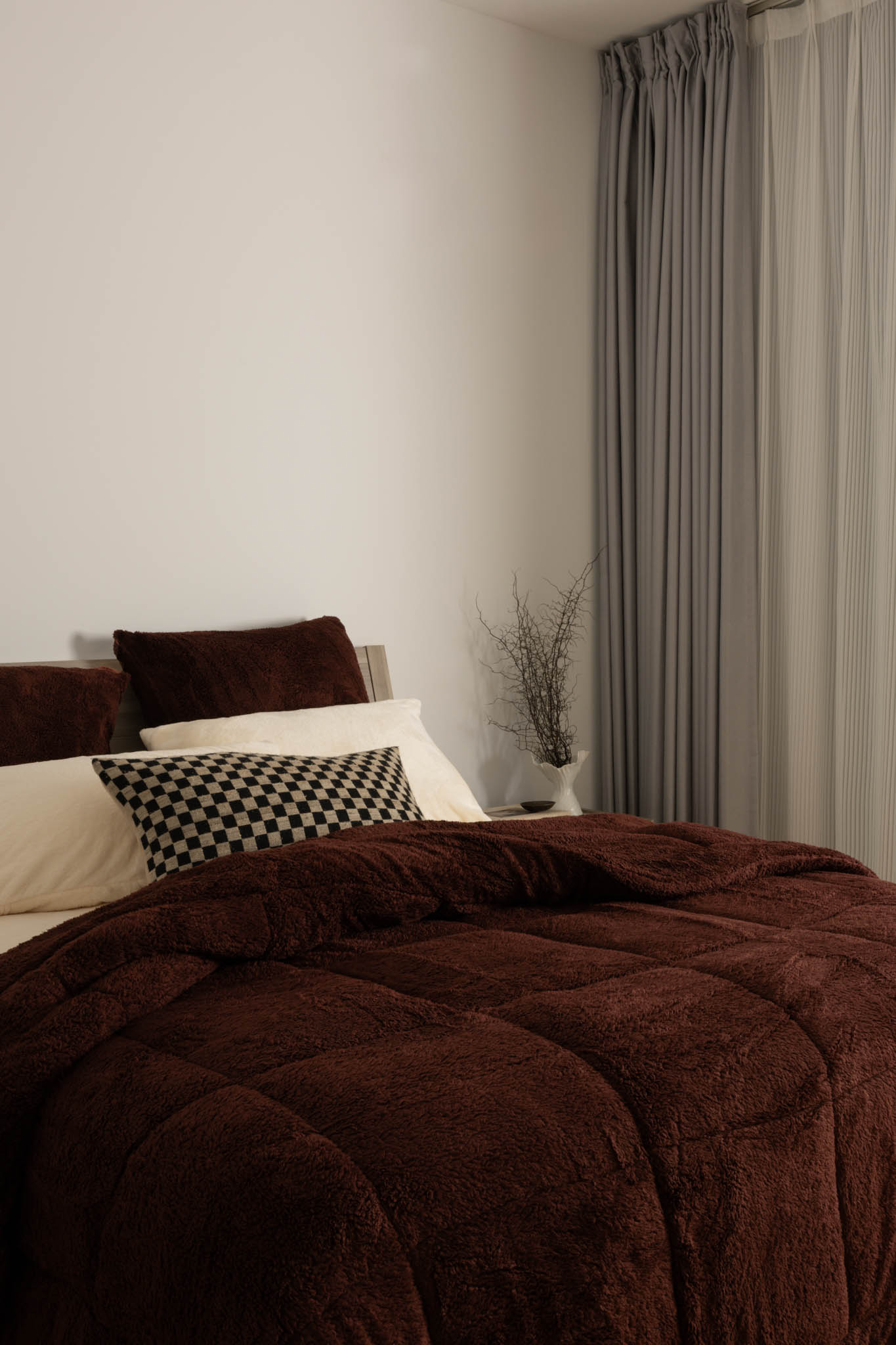 Brown comforter on a bed with pillows in a bedroom setting.