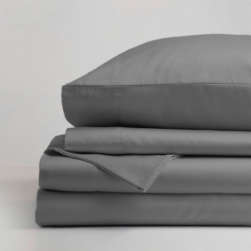 The Morgan and Reid Hotel 1500 Thread Count Cotton Rich Sheet Set, with pillowcases and one pillow on top, is neatly stacked and displayed against a plain light gray background.