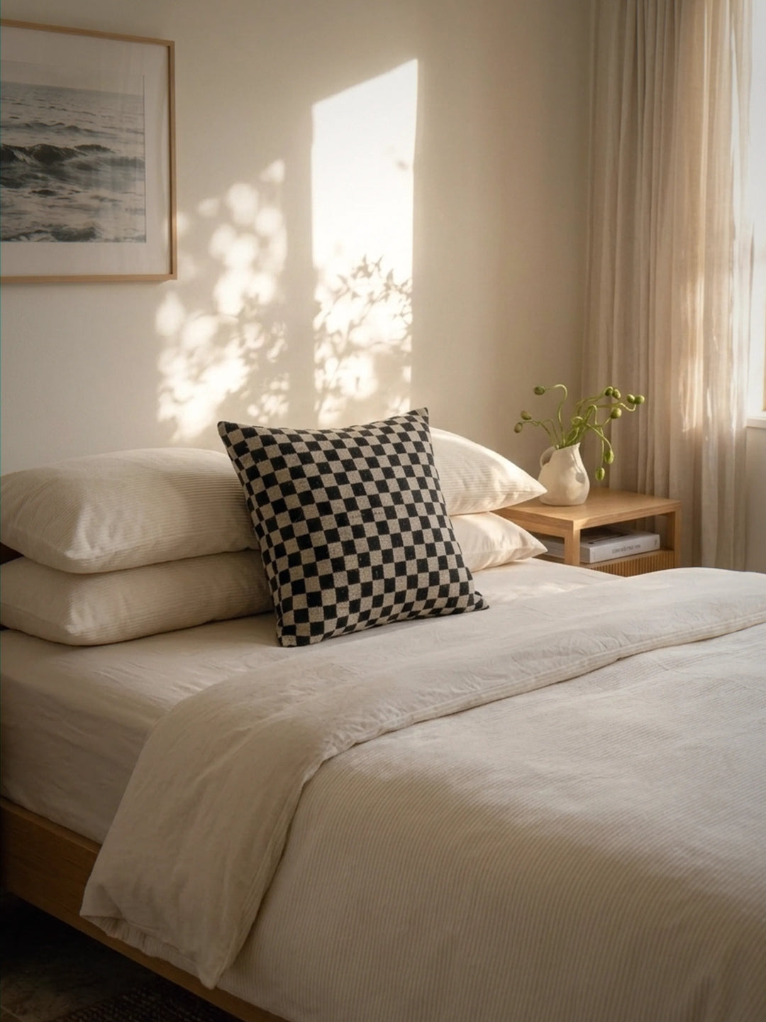 Neatly made bed with checkered pillow in a softly lit bedroom