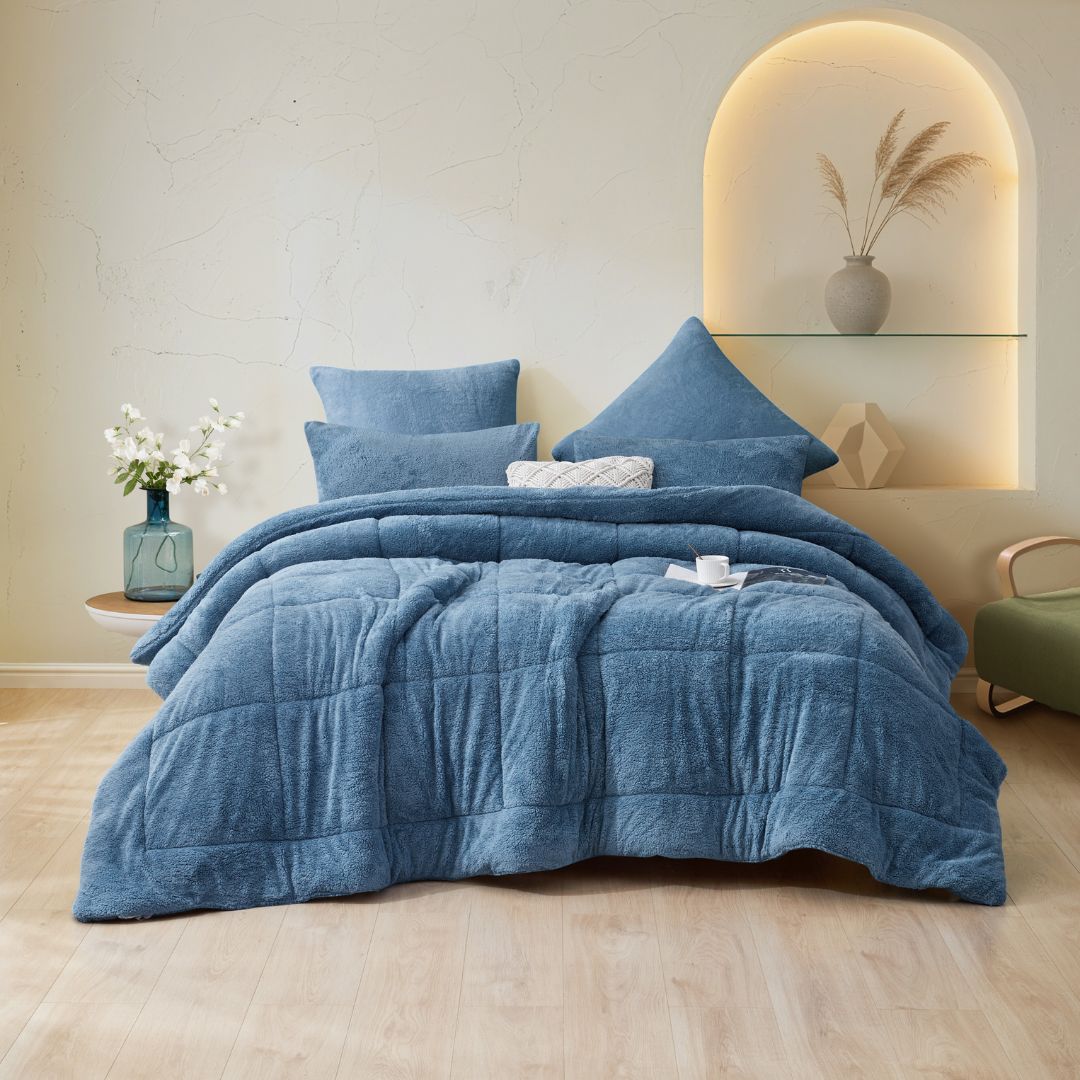 Blue comforter set on a bed in a bedroom with decorative elements.
