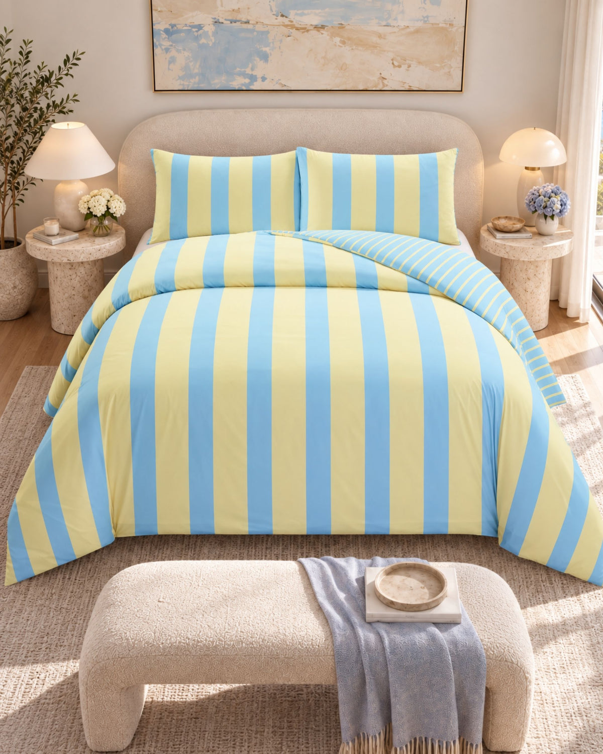 A bed dressed in a light blue and pale yellow striped bedding set, shown in a styled bedroom with matching pillows, bedside tables, lamps, and a bench at the foot of the bed.
