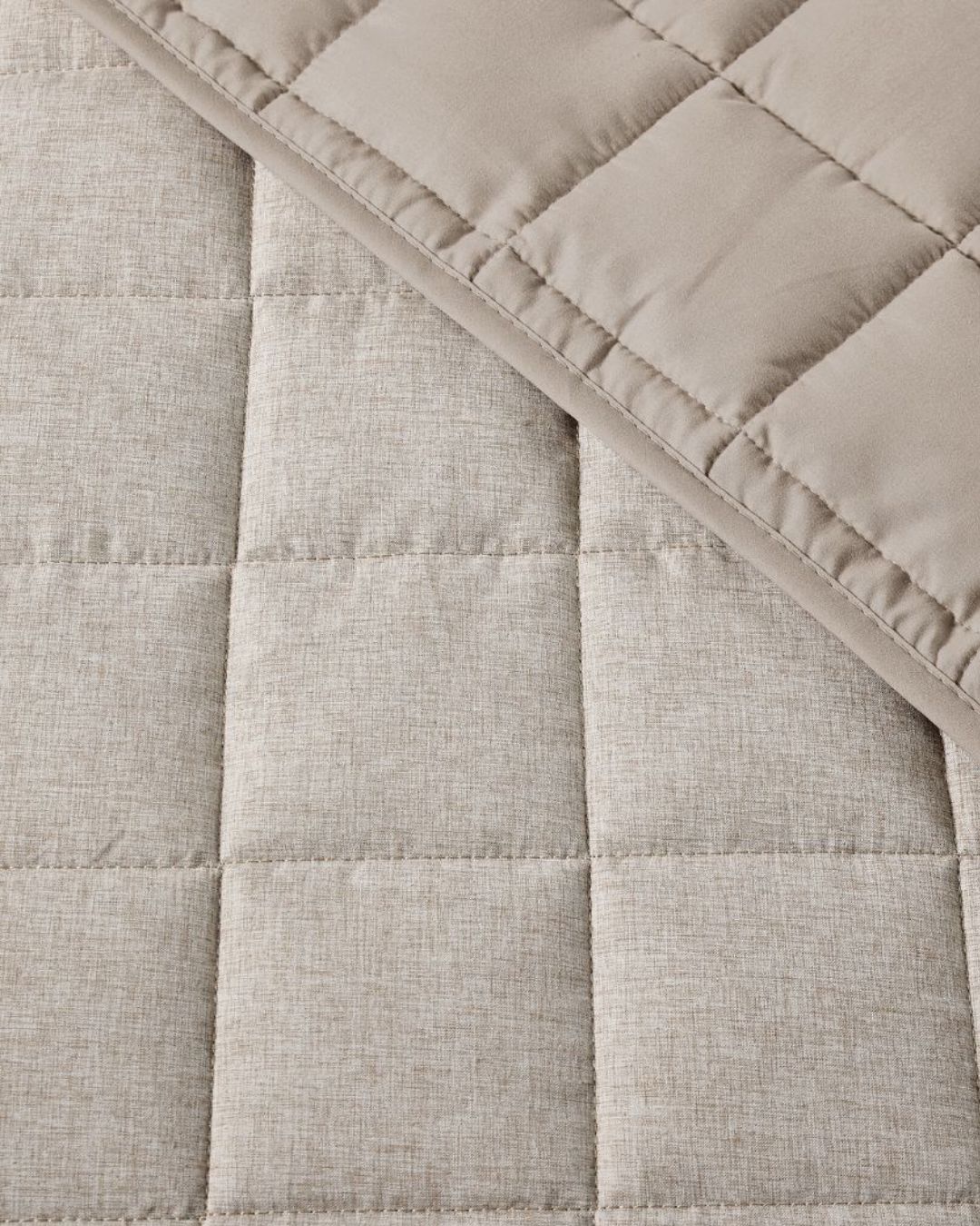 Close-up of a quilted fabric with a diamond pattern in beige color.