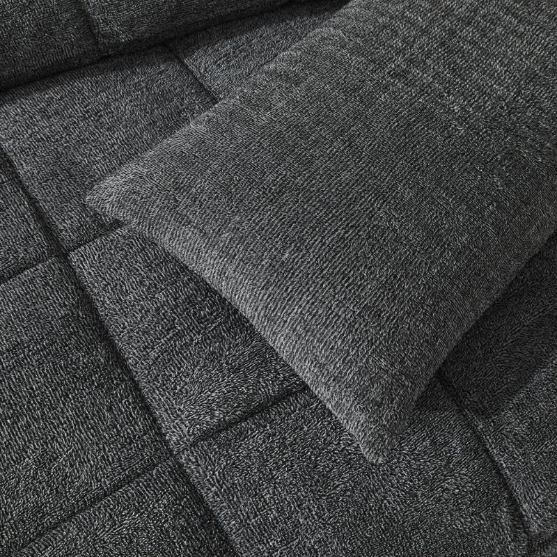 A rectangular, dark gray textured pillow is shown against a white background, ideal for cosy bedding. Pair it with the Morgan and Reid Black White Snuggle Fleece Pillowcase Pair for style and comfort.