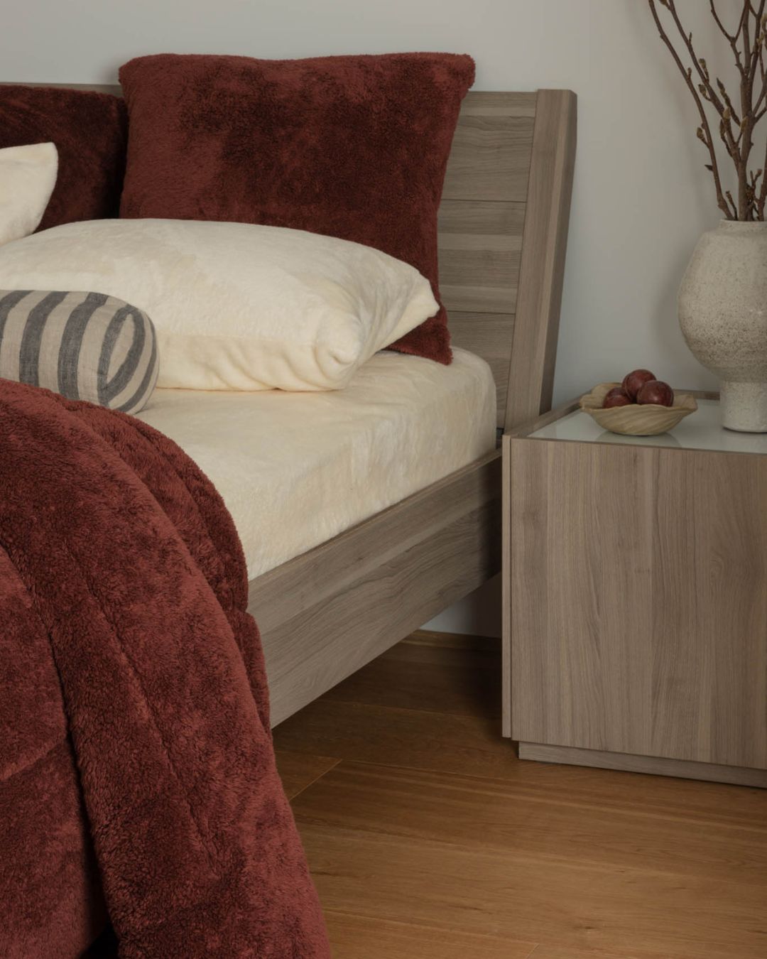 Bedroom with wooden bed and nightstand, featuring pillows and a blanket.