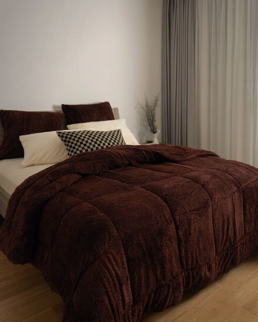 Brown textured comforter on a bed with pillows in a bedroom setting.
