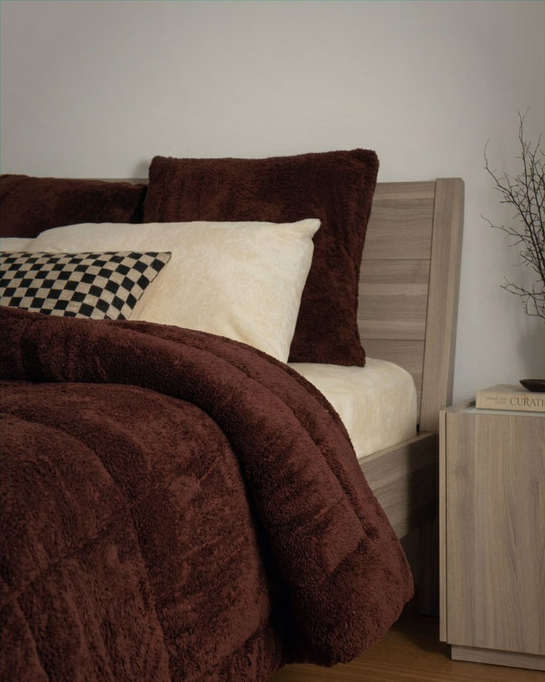 Bed with brown comforter and pillows in a bedroom setting.