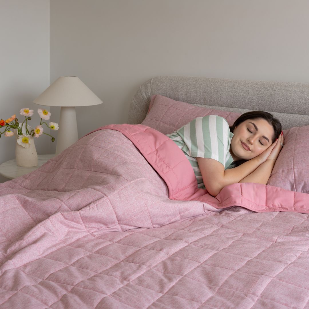 Woman sleeping in a bed with pink bedding and striped pillow