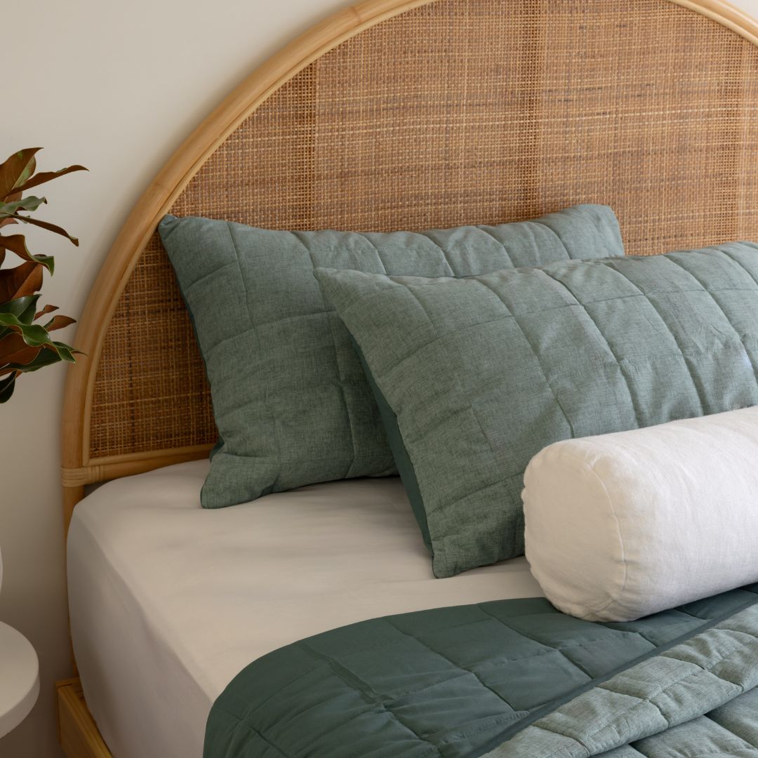 Bed with green pillows and a wicker headboard