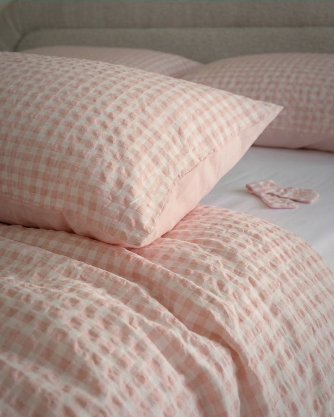 Pink checkered bedding set on a bed with pillows.