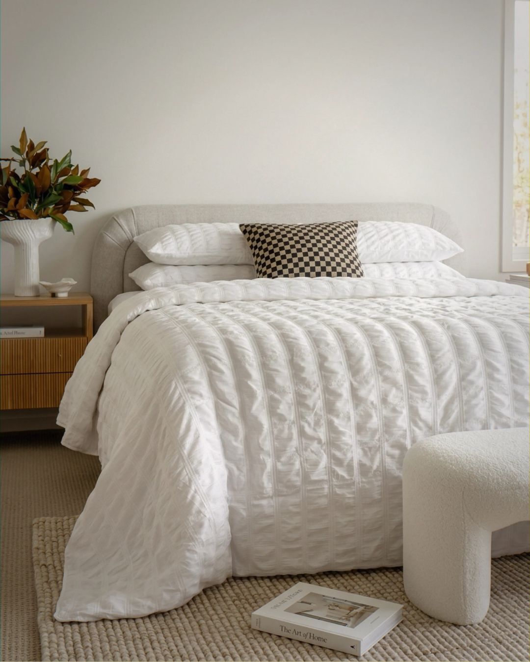 Neatly made bed with white bedding in a bedroom setting.