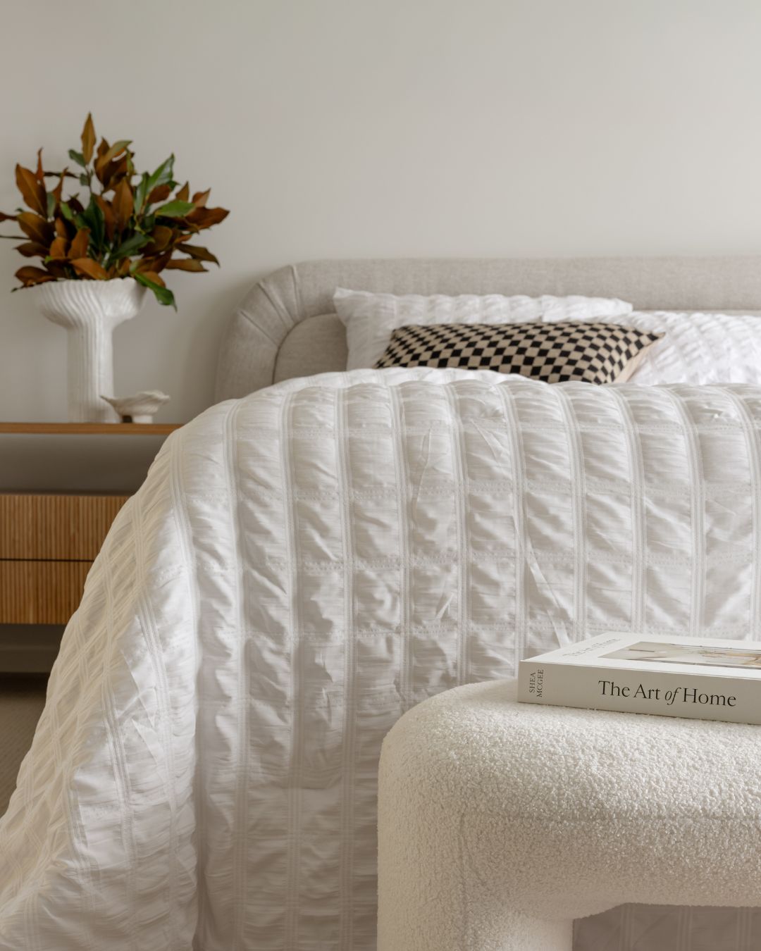 Neatly made bed with white bedding in a bedroom setting.