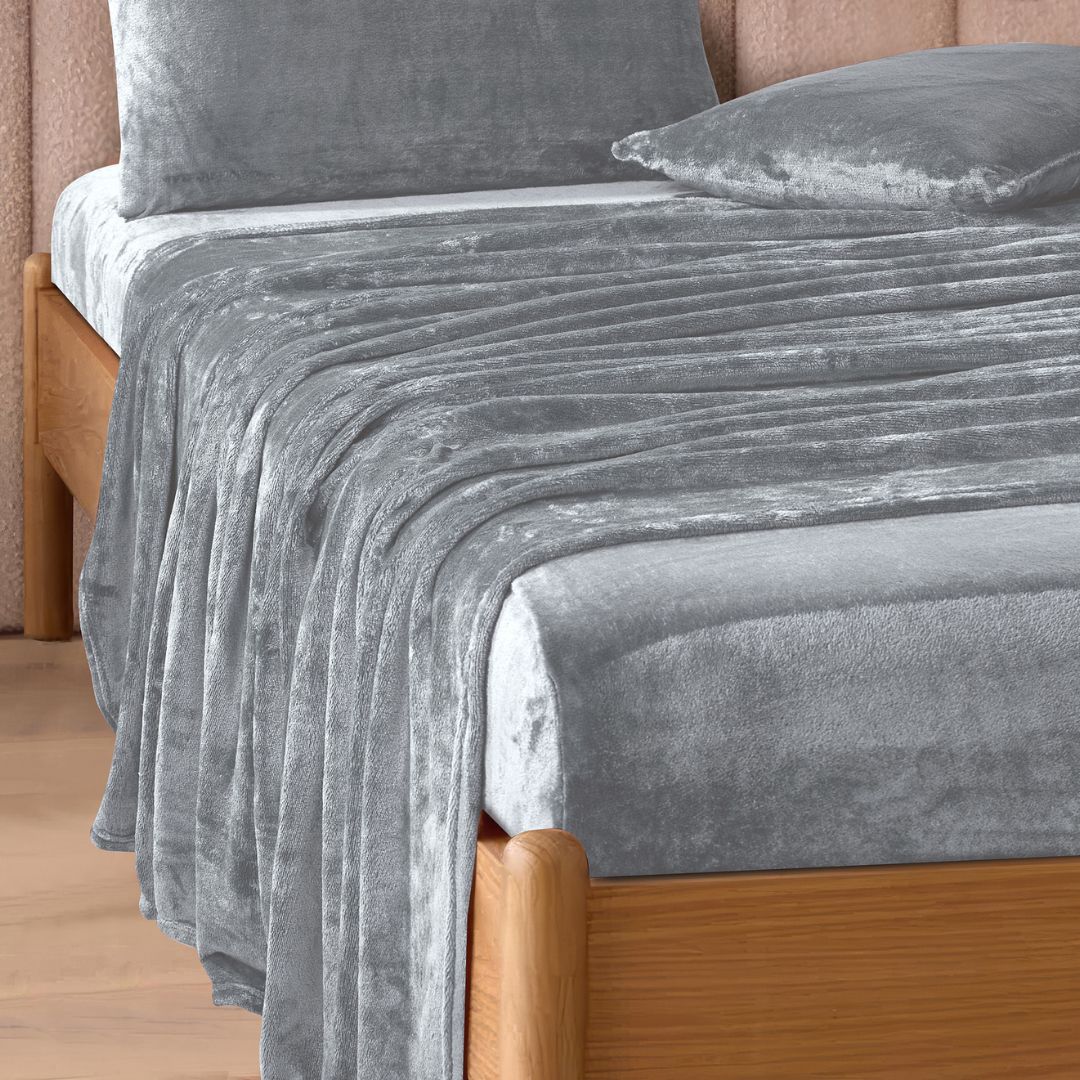 A modern bedroom with a beige upholstered bed and cream bedding exudes winter comfort, enhanced by the Morgan and Reid Winter Microplush Sheet Sets ultra-soft fabric, neutral decor, dried flowers, and light wood floors.