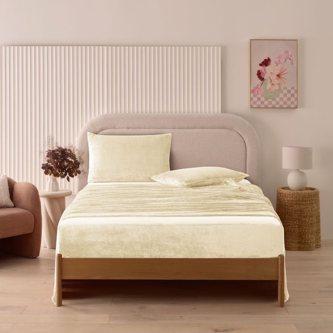 A modern bedroom with a beige upholstered bed and cream bedding exudes winter comfort, enhanced by the Morgan and Reid Winter Microplush Sheet Sets ultra-soft fabric, neutral decor, dried flowers, and light wood floors.