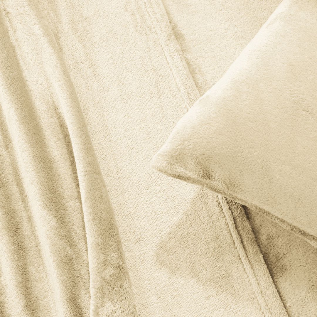 A modern bedroom with a beige upholstered bed and cream bedding exudes winter comfort, enhanced by the Morgan and Reid Winter Microplush Sheet Sets ultra-soft fabric, neutral decor, dried flowers, and light wood floors.