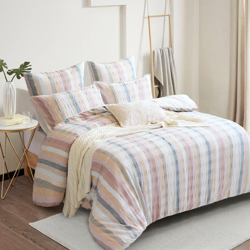Styled bed featuring Renee Taylor Layla European Pillowcases in blush, peach, and grey tones.
