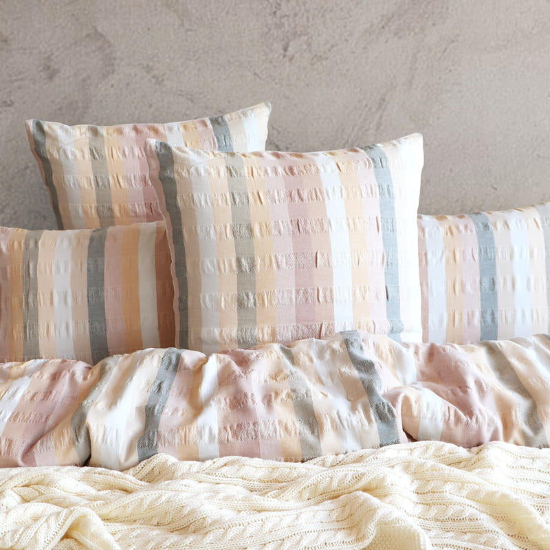 Styled bed featuring Renee Taylor Layla European Pillowcases in blush, peach, and grey tones.