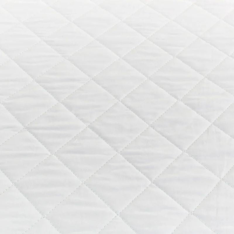 Close-up of the Sienna Living Premium Cotton Mattress Protector featuring a quilted cotton japara cover and diamond stitch pattern, fitted securely over a mattress with a grey upholstered base. Knit stretch skirt ensures a snug fit around corners.