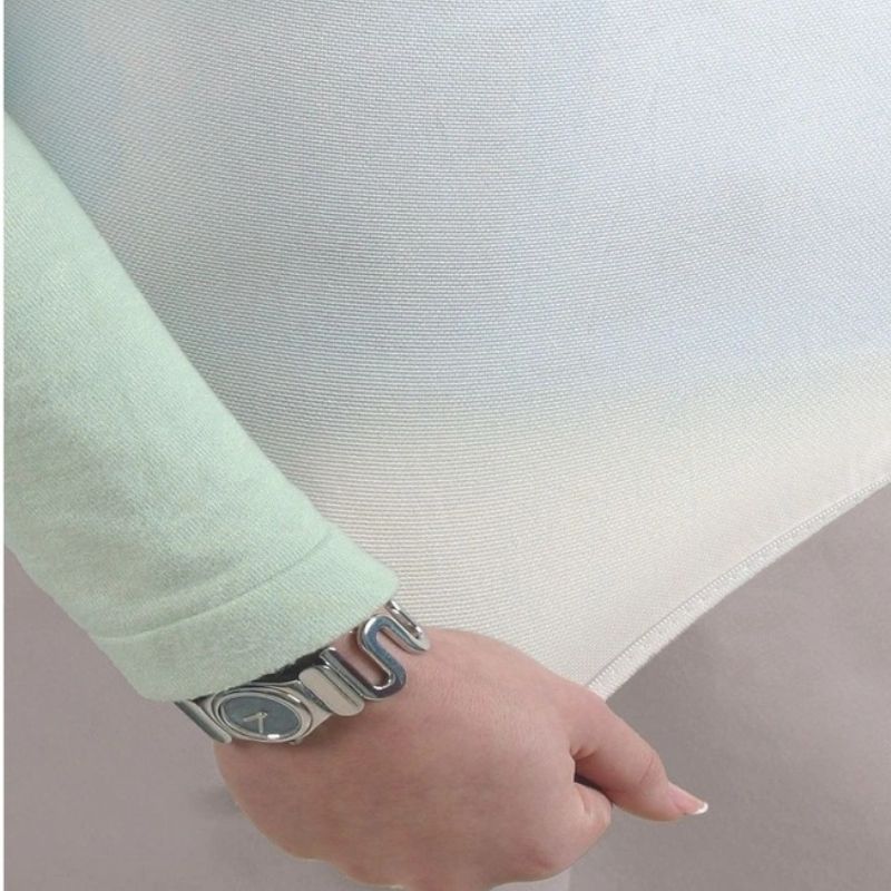 Close-up of the Sienna Living Premium Cotton Mattress Protector featuring a quilted cotton japara cover and diamond stitch pattern, fitted securely over a mattress with a grey upholstered base. Knit stretch skirt ensures a snug fit around corners.