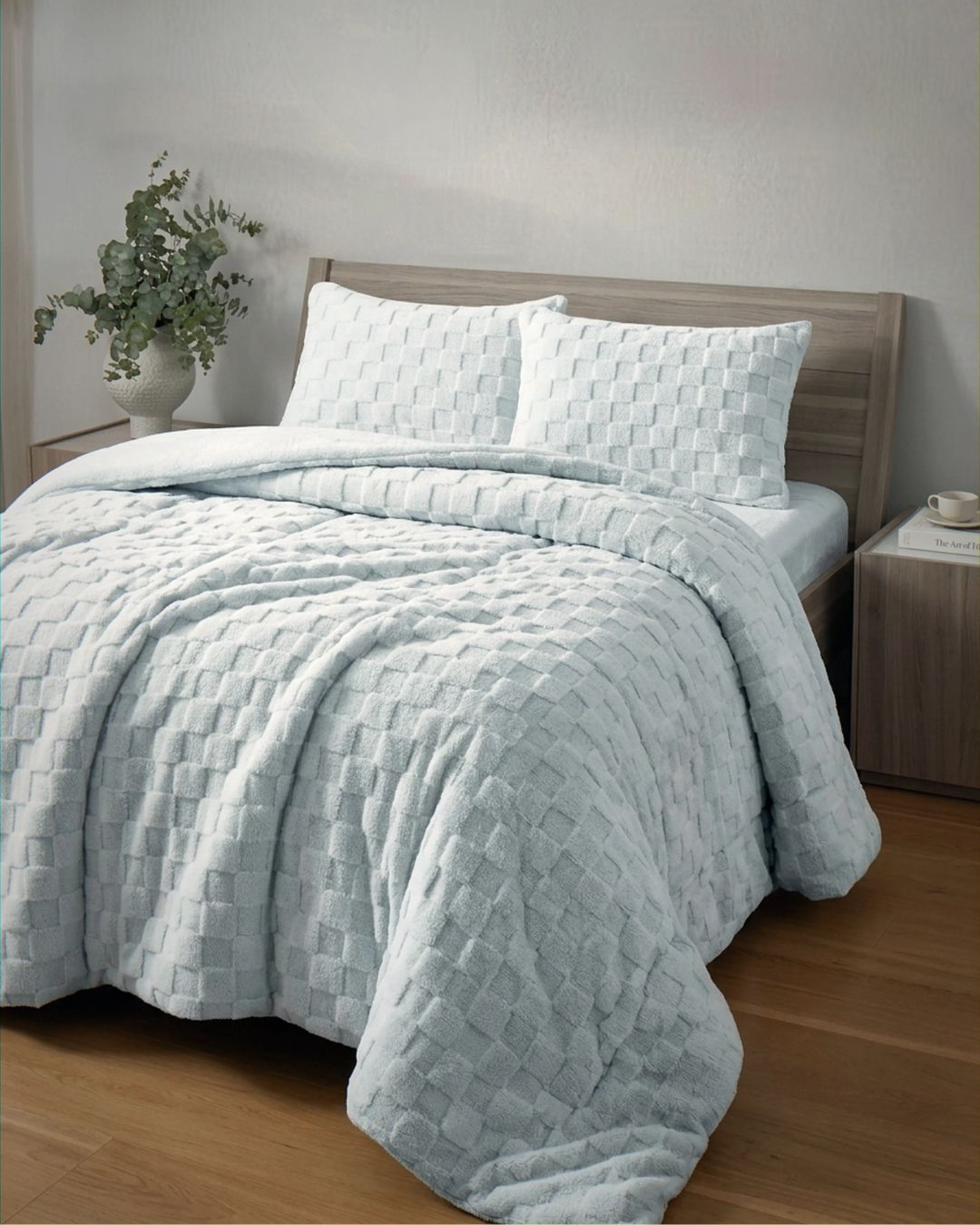 Soft blue checkered snuggle fleece comforter set styled on a bed with matching pillow shams