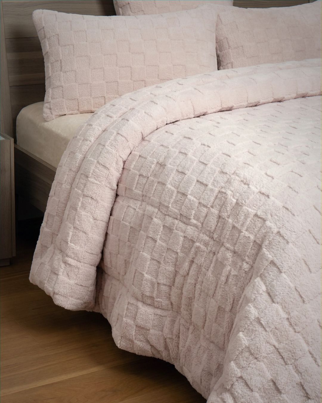 Soft pink checkered snuggle fleece comforter set styled on bed, showing plush quilted texture detail with matching pillowcases.