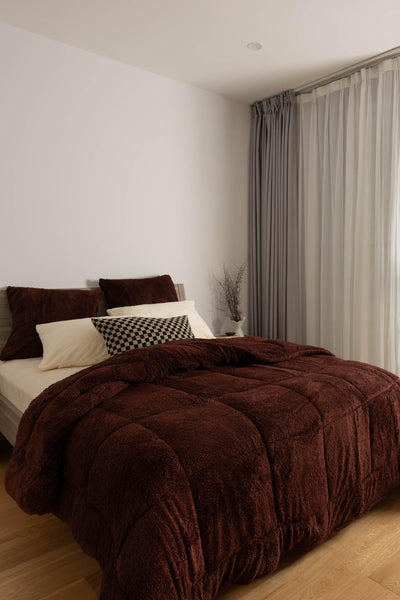 Bedroom with a bed covered in a brown comforter and pillows.