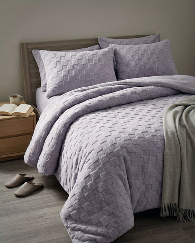 Lavender checkered snuggle fleece comforter set styled on bed with matching shams and gray throw blanket
