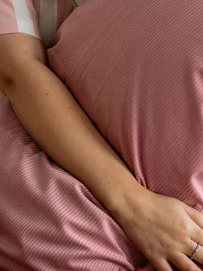 Close-up of a person's arm and hand resting on a pink textured surface.