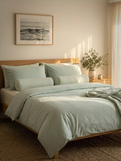 Neatly made bed with light green bedding in a bedroom setting.
