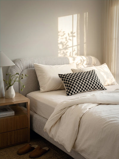 Neatly made bed with checkered pillow in a bright bedroom