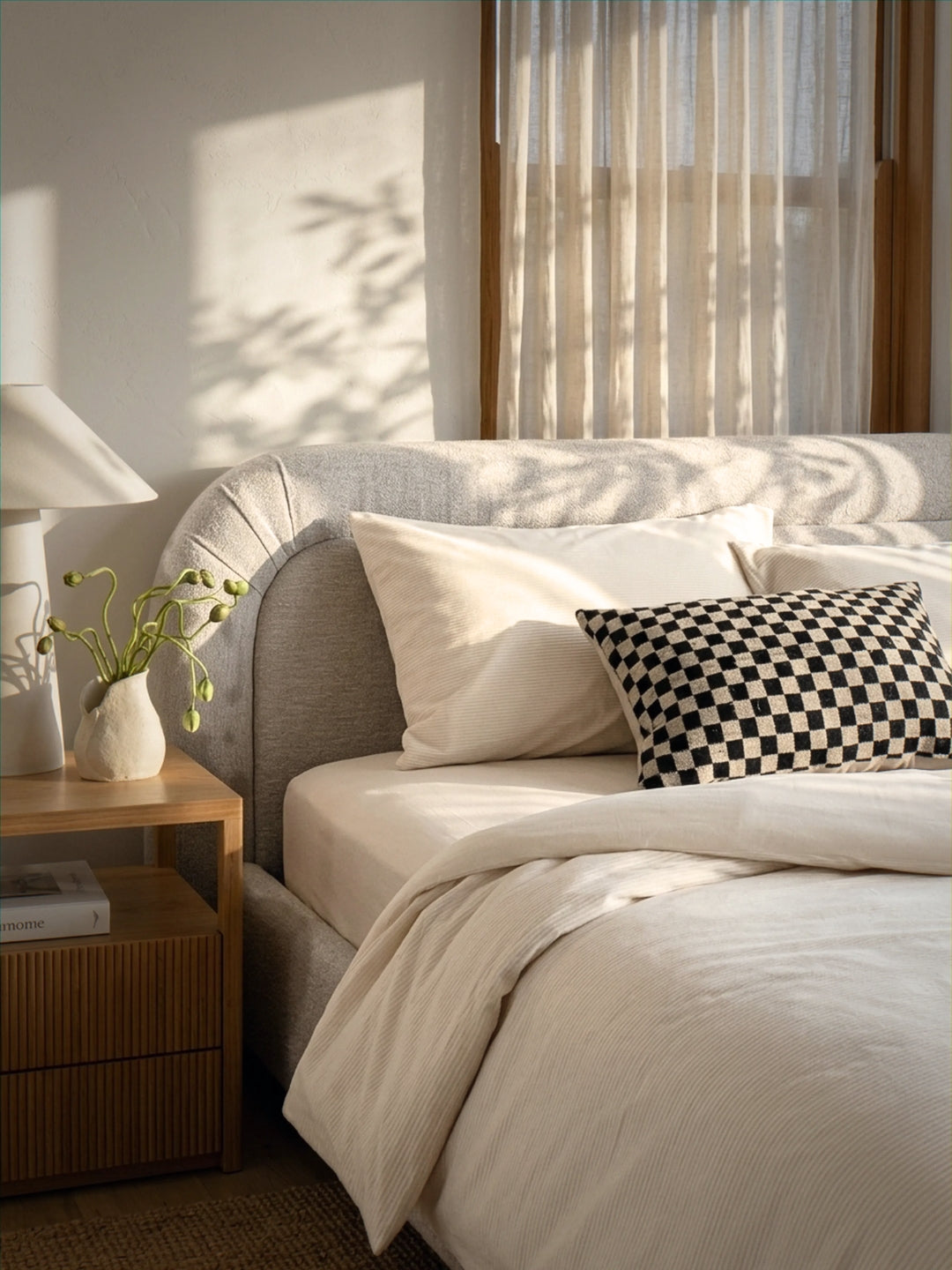 Neatly made bed with decorative pillows in a bedroom setting.