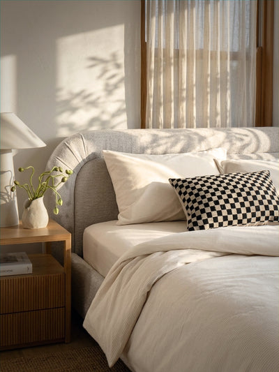 Neatly made bed with decorative pillows in a bedroom setting.