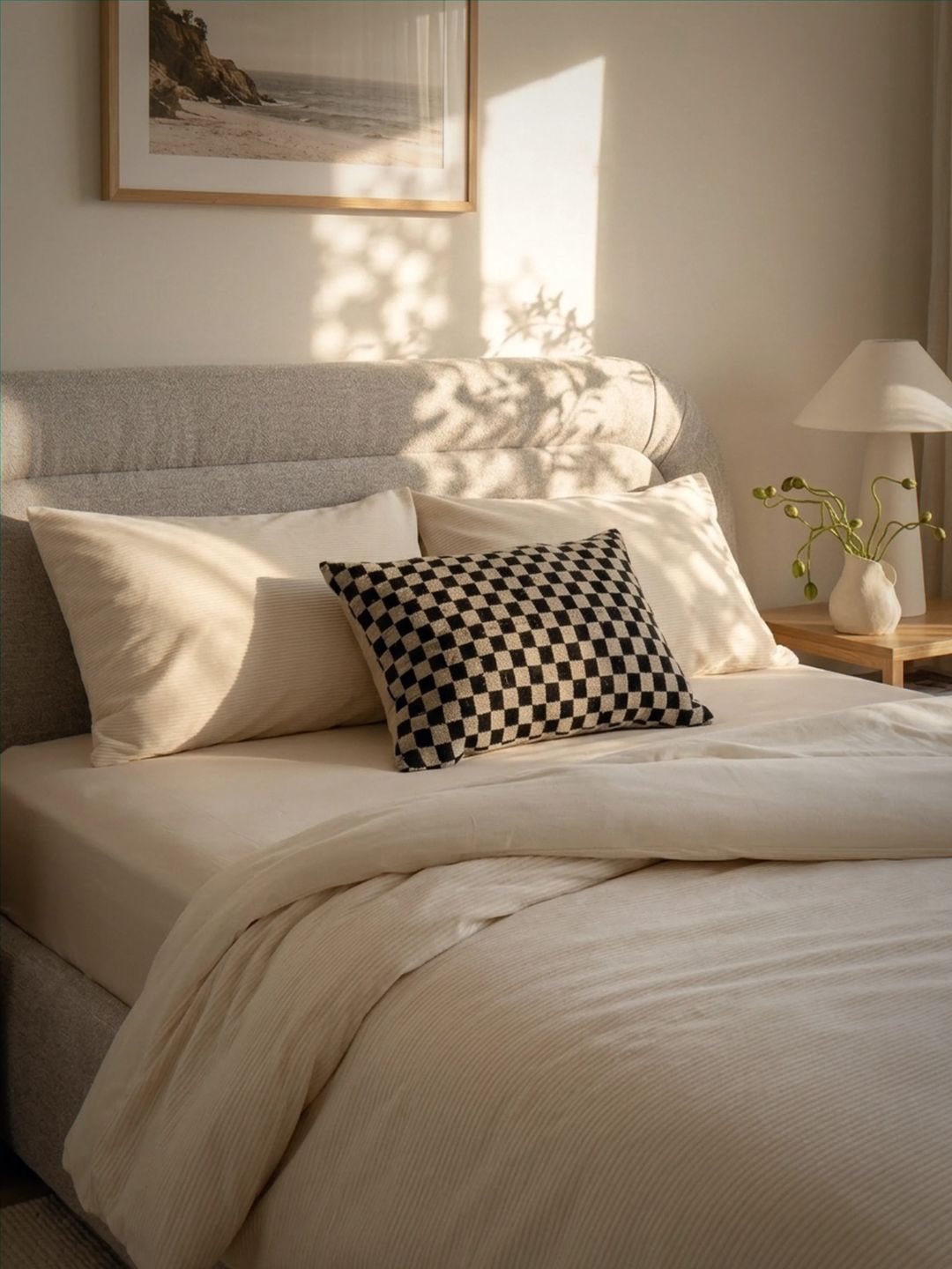 Neatly made bed with decorative pillows in a softly lit bedroom.