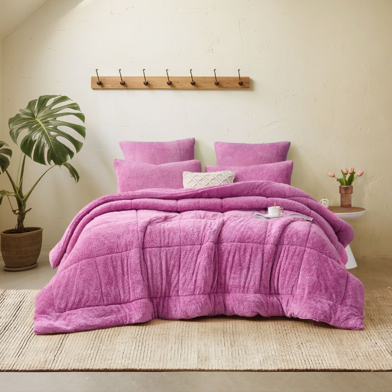 A vibrant crocus pink Snuggle Fleece Comforter set with layered pillows, adding warmth and colour to a modern bedroom.