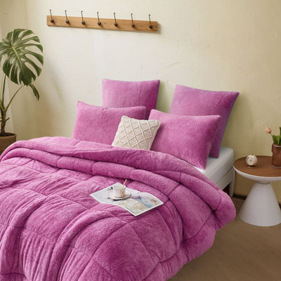 A vibrant crocus pink Snuggle Fleece Comforter set with layered pillows, adding warmth and colour to a modern bedroom.
