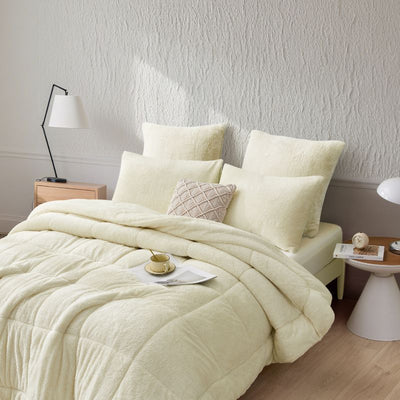 An ivory Snuggle Fleece Comforter set styled in a bright bedroom with a soft rug and timber accents for a calm, welcoming feel.