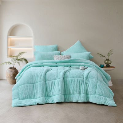 Turquoise quilt and pillow set on a bed in a bedroom setting.