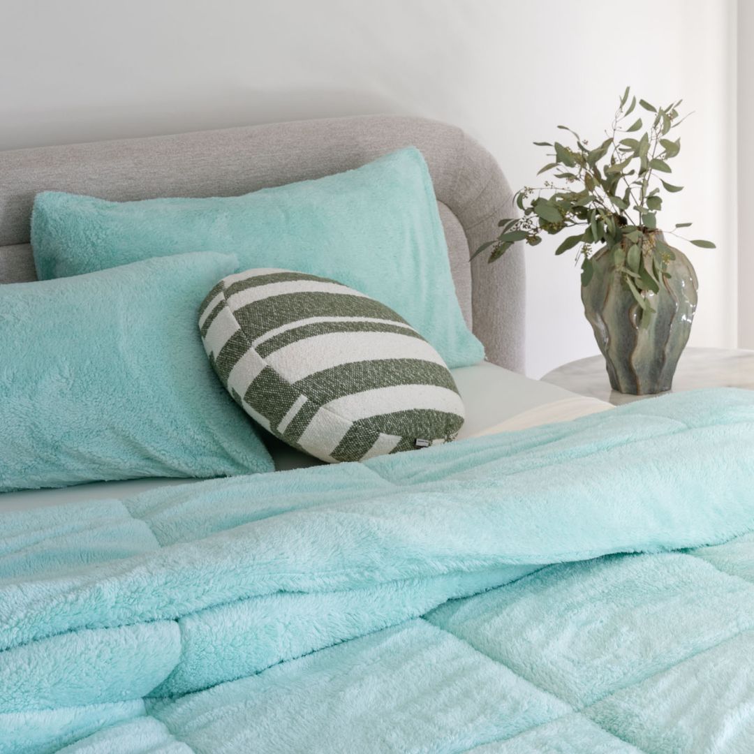 Bed with teal bedding and pillows in a bedroom setting