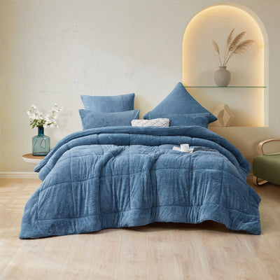 Blue comforter set on a bed in a bedroom with decorative elements.