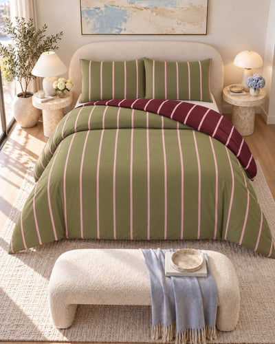 A styled bedroom scene showing a bed made with an olive green striped bedding set, including a duvet cover and two matching pillow shams. A folded burgundy throw blanket is draped over the foot of the bed.