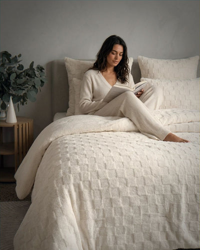 Woman reading a book on a bed with neutral tones