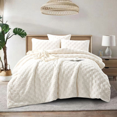 A neatly made bed showcases the Morgan and Reid Checkered Cream Snuggle Fleece Comforter Set with textured pillows, against a light wall, paired with a wooden headboard, bedside table, lamp, and a large leafy plant.