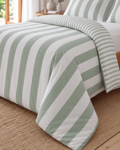Green and white striped bedding set with a duvet cover and matching pillowcases, styled on a bed over a woven jute rug.