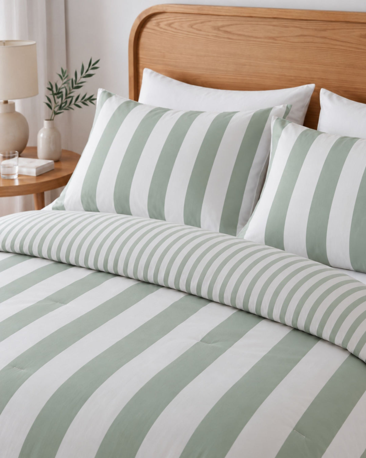 Green and white striped bedding set with matching pillowcases and a duvet cover, styled on a bed with a wooden headboard in a bedroom setting.
