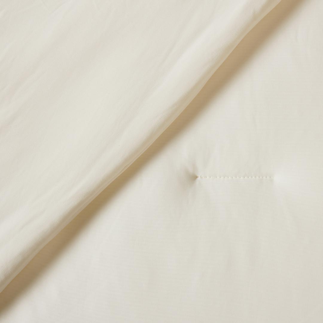 Lightweight coconut cooling comforter layered on rattan bed frame.