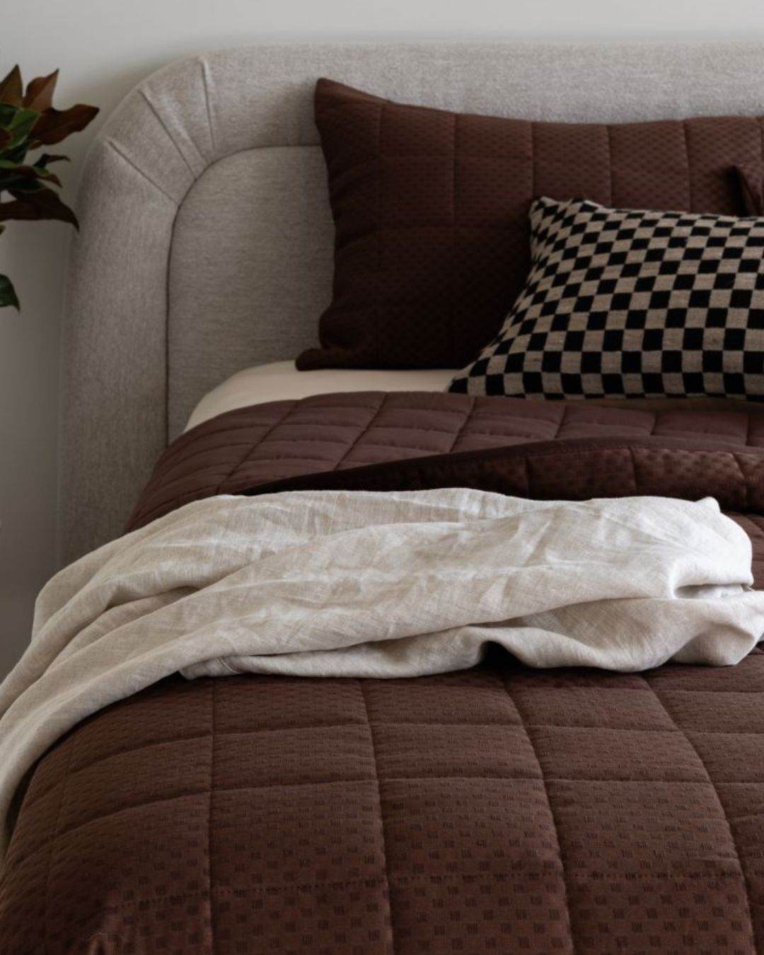 Bed with brown bedding and pillows in a cozy bedroom setting