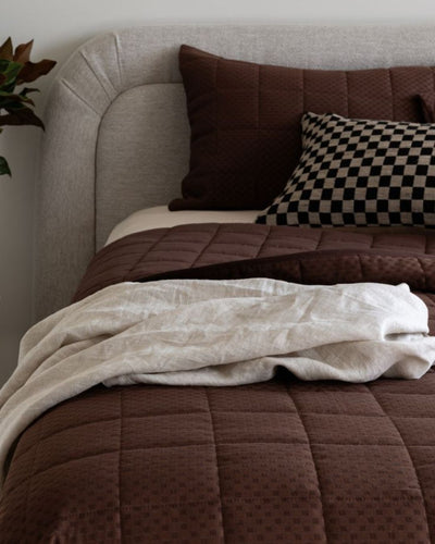 Bed with brown bedding and pillows in a cozy bedroom setting