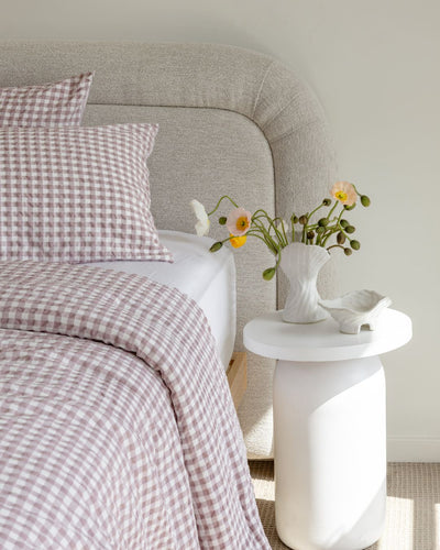 Bedroom with checkered bedding and a vase of flowers on a nightstand.