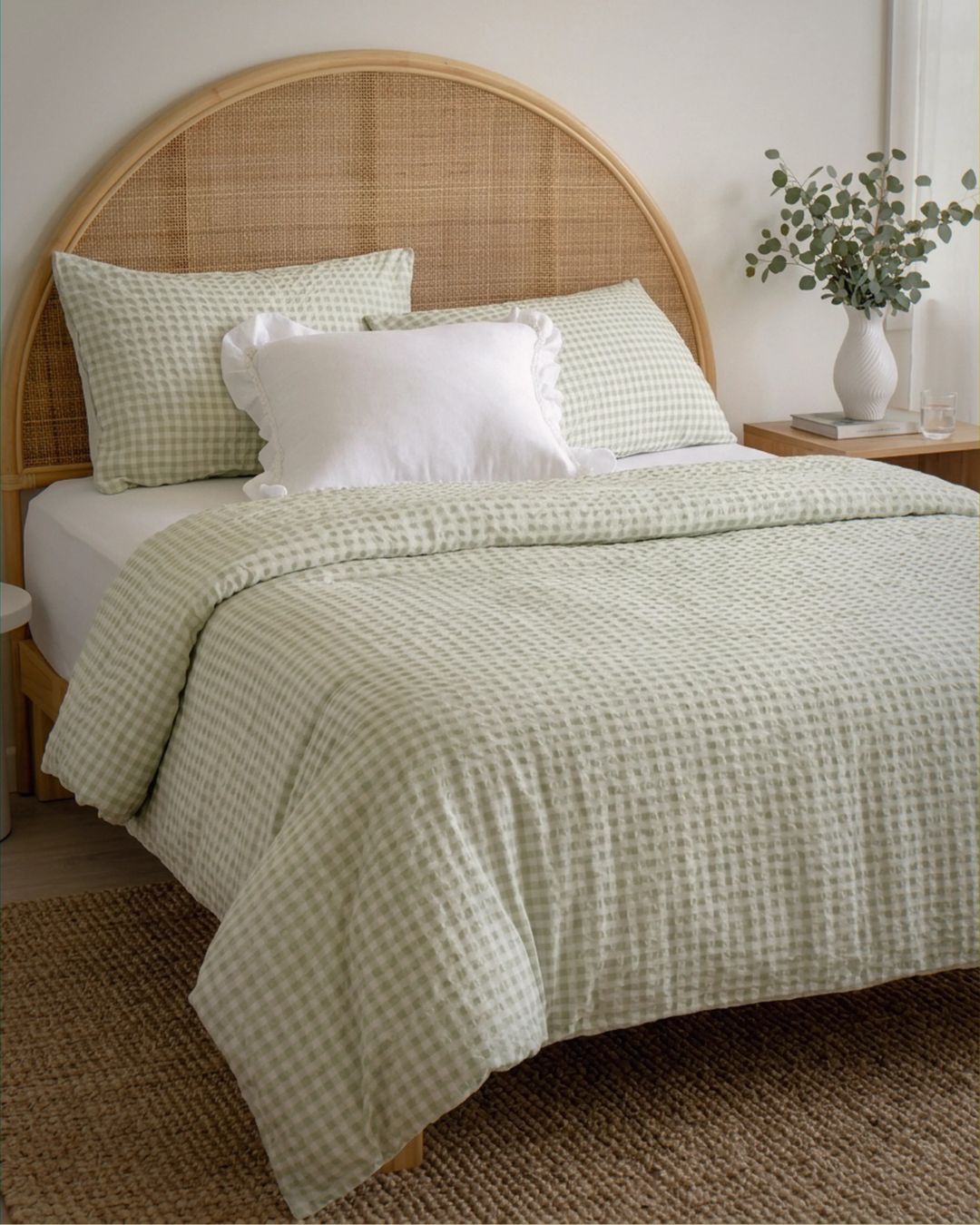 Bed with green checkered bedding and wicker headboard in a bedroom setting.