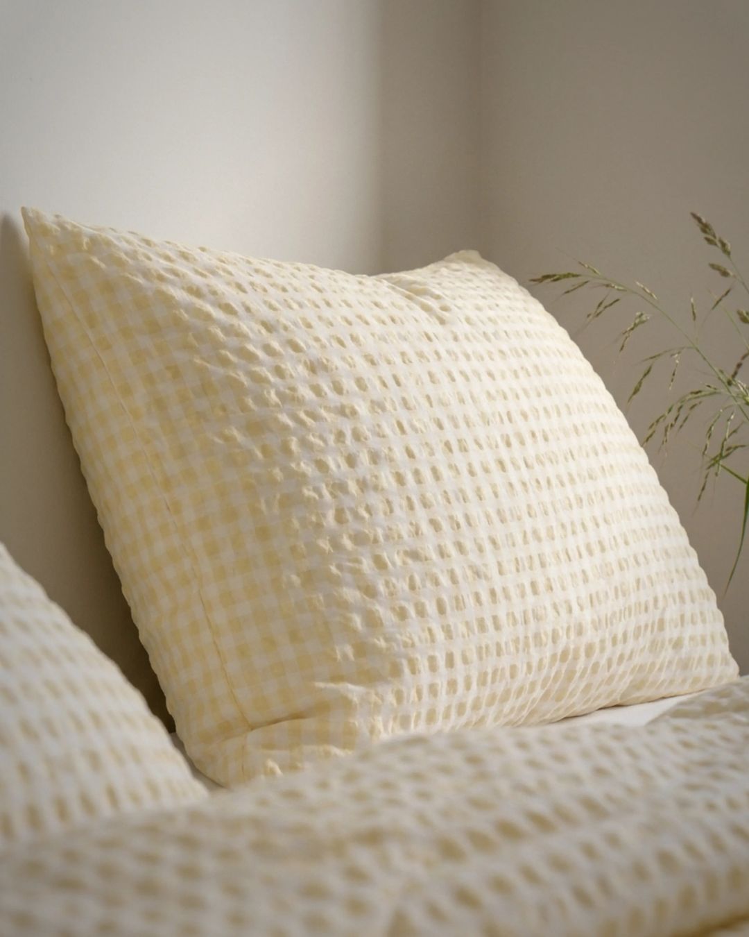 Textured yellow pillow on a bed with a neutral background
